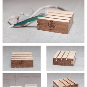May include: A wooden stand made of sycamore wood with a Native Circles logo. The stand has four sides and is designed to hold items like jewelry or other small objects. The stand is made of natural wood and has a rustic look.