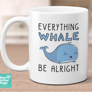 K&ouml;nnte beinhalten: Wei&szlig;e Keramiktasse mit dem Text "EVERYTHING WHALE BE ALRIGHT" und einer Cartoon-Illustration eines blauen Wals. Die Tasse hat einen gebogenen Henkel und eine gl&auml;nzende Oberfl&auml;che. Das Nine Dollar Mugs Logo ist sichtbar.
