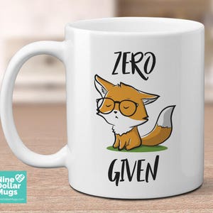以下が含まれることがあります： メガネをかけた漫画のキツネと「ZERO GIVEN」の文字が描かれた白いセラミックマグ。キツネはオレンジと白で、緑の草の上に座っています。面白いデザインです。