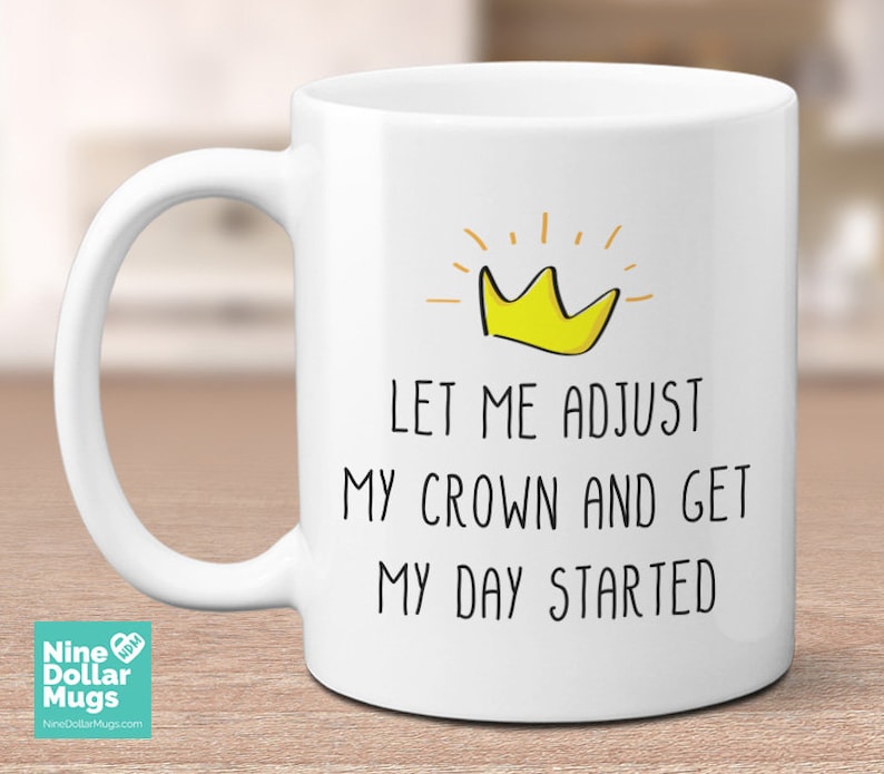 May include: White ceramic mug with the text "LET ME ADJUST MY CROWN AND GET MY DAY STARTED" and a yellow crown graphic. The mug has a large handle and is suitable for hot or cold beverages.