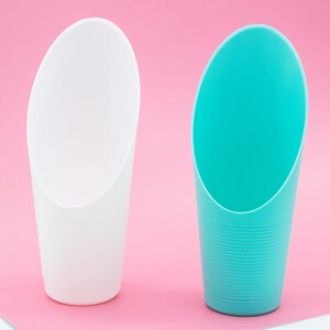 May include: Two plastic scoops, one white and one turquoise blue, are shown against a pink background. The scoops are designed for scooping soil or other loose materials.