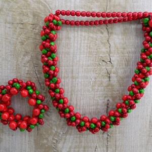 May include: A red and green beaded necklace and bracelet set. The necklace is long and the bracelet is small and round.