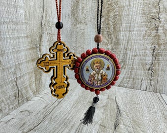 May include: Two wooden car charms, one a cross with Greek lettering and the other a round icon with a red beaded frame and a picture of a saint.