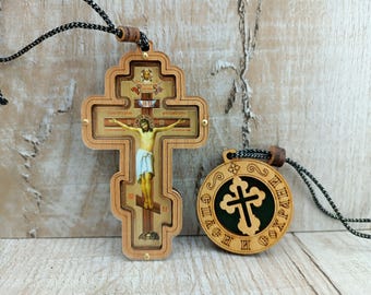 May include: Two wooden pendants with a black cord. The first pendant is a cross with a detailed image of Jesus Christ on the cross. The second pendant is a round disc with a cross cut out of the center. The text on the disc reads "Слава Богу" in Cyrillic.