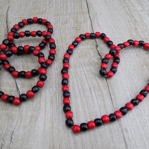 May include: A set of three black and red beaded bracelets and a longer black and red beaded necklace. The necklace is shaped into a heart.