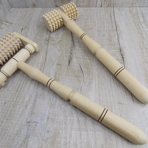 May include: Two wooden massage rollers with spiked wheels. The rollers have wooden handles with black lines.