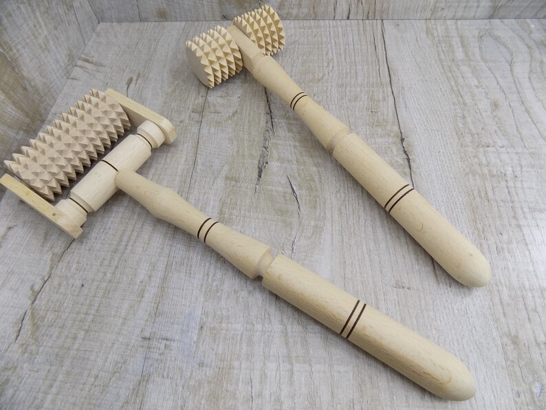 May include: Two wooden massage rollers with spiked wheels. The rollers have wooden handles with black lines.