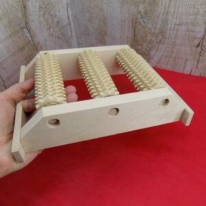 May include: Wooden foot massage roller with three rollers. The rollers have a textured surface and are mounted on a wooden frame.