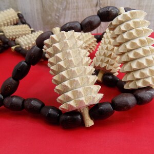 May include: A wooden massage roller with brown beads. The roller has a series of pointed spikes and is designed for self-massage.
