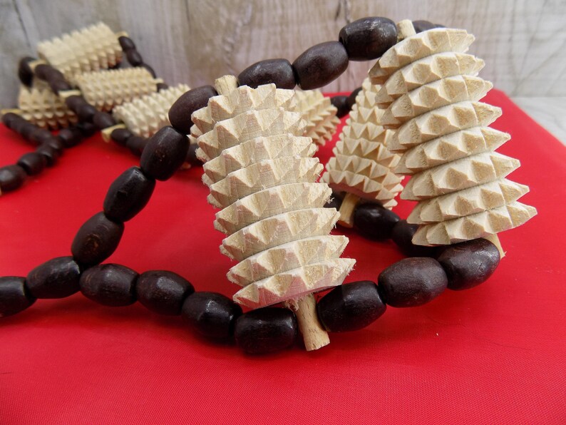 May include: A wooden massage roller with brown beads. The roller has a series of pointed spikes and is designed for self-massage.