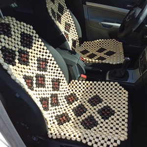 Puede incluir: Un par de cojines para asientos de coche de cuentas de madera beige y marrón. Los cojines están hechos de pequeñas cuentas redondas que están entrelazadas en un patrón de diamante.