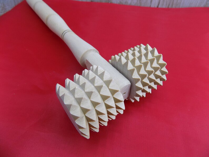 May include: A wooden rolling pin with a handle and two sets of spiked wheels. The wheels are made of wood and have a light brown color.