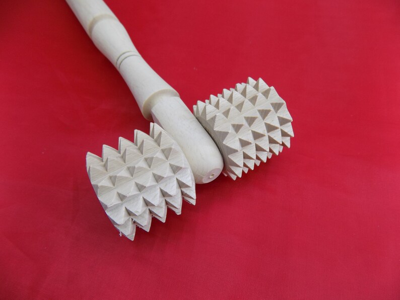 May include: A wooden rolling pin with two spiked wheels. The wheels are made of wood and have a triangular pattern.