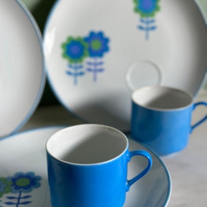 Puede incluir: Un juego de tazas de t&eacute; y platillos con estampado floral azul y blanco. Las tazas son de color azul brillante con interior blanco y borde blanco. Los platillos son blancos con borde azul y un dise&ntilde;o floral en azul, verde y blanco.