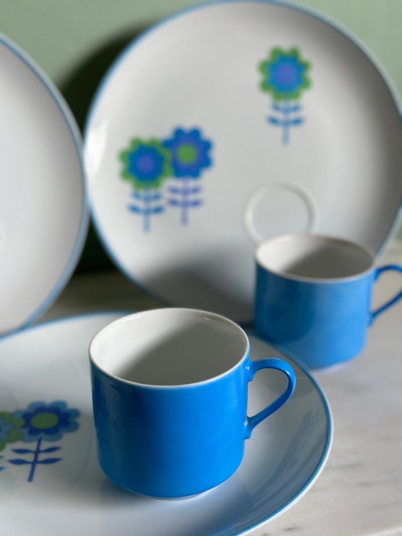 Puede incluir: Un juego de tazas de t&eacute; y platillos con estampado floral azul y blanco. Las tazas son de color azul brillante con interior blanco y borde blanco. Los platillos son blancos con borde azul y un dise&ntilde;o floral en azul, verde y blanco.