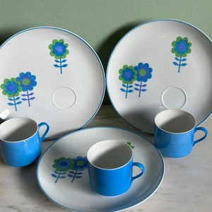 Puede incluir: Juego de tres platos de cer&aacute;mica azul y blanco con un dise&ntilde;o floral. Los platos tienen un borde elevado y una peque&ntilde;a hendidura para una taza. Las tazas tambi&eacute;n son azules y blancas.