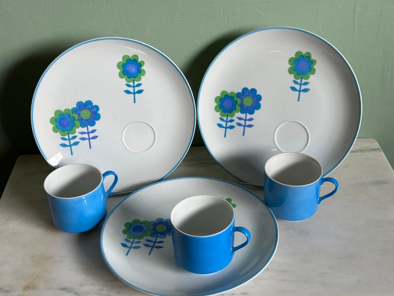 Puede incluir: Juego de tres platos de cer&aacute;mica azul y blanco con un dise&ntilde;o floral. Los platos tienen un borde elevado y una peque&ntilde;a hendidura para una taza. Las tazas tambi&eacute;n son azules y blancas.