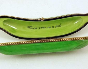 May include: A green pea pod shaped trinket box with a gold trim and the inscription "Two peas in a pod" on the inside.