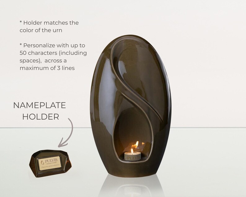 May include: A dark brown, egg-shaped urn with a glossy finish. A small candle burns inside a recessed area. A nameplate holder is included. The text on the nameplate holder reads "PULVIS".