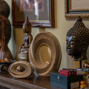 The Passage is a unique art urn for ashes. It represents a spiral with a hole in the middle. The ashes go inside the walls and there is a candle that when lit reflects on the inner side of the urn. This is a photo of a large urn and keepsake.