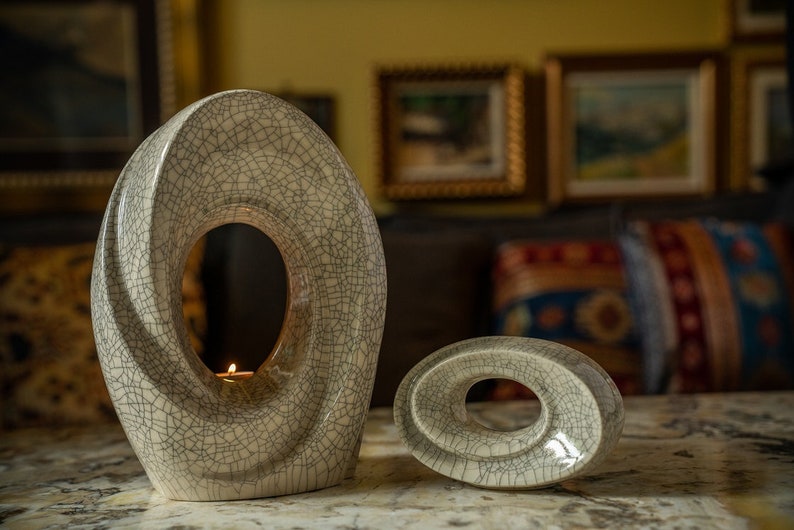 The Passage is a unique art urn for ashes. It represents a spiral with a hole in the middle. The ashes go inside the walls and there is a candle that when lit reflects on the inner side of the urn. This is a photo of a large urn and keepsake.