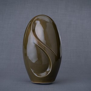 Adult size urn for ashes Eternity. The urn represents a straight ellipse with a hint of the infinity symbol all along its length. There is a place for a candle in the bottom half of the urn. This ceramic art urn comes in a various colors. By Pulvis