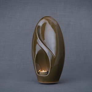 Adult size urn for ashes Eternity. The urn represents a straight ellipse with a hint of the infinity symbol all along its length. There is a place for a candle in the bottom half of the urn. This ceramic art urn comes in a various colors. By Pulvis