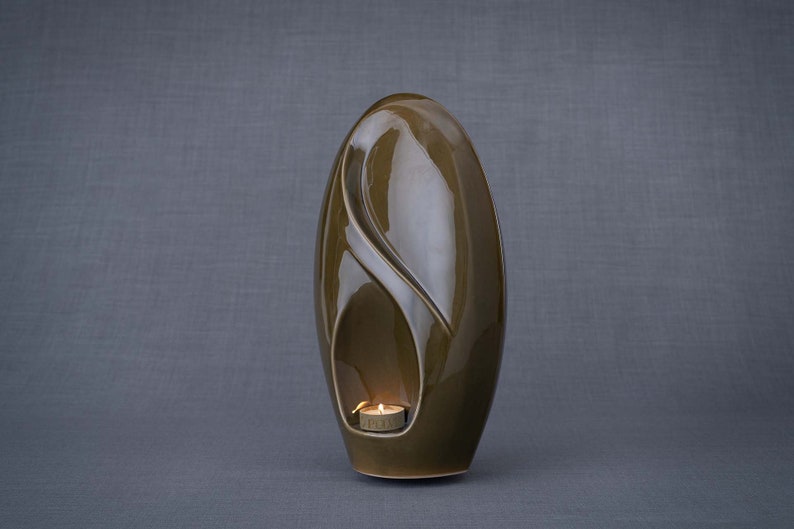 Adult size urn for ashes Eternity. The urn represents a straight ellipse with a hint of the infinity symbol all along its length. There is a place for a candle in the bottom half of the urn. This ceramic art urn comes in a various colors. By Pulvis