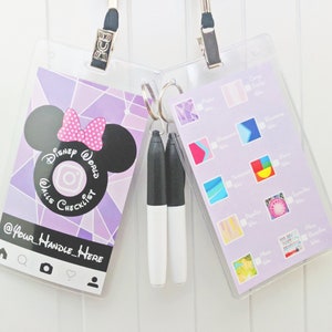 May include: A purple and white checklist card with a Mickey Mouse silhouette and the text "Disney World Walls Checklist" and "@Your Handle Here". The card is hanging from a clear plastic lanyard with a silver clip. Two black and white markers are hanging from a silver ring.