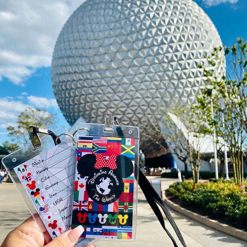May include: A clear plastic badge holder with a colorful design featuring flags from around the world. The badge holder has a Mickey Mouse ear design and the text "Drinking Around the World 2021".