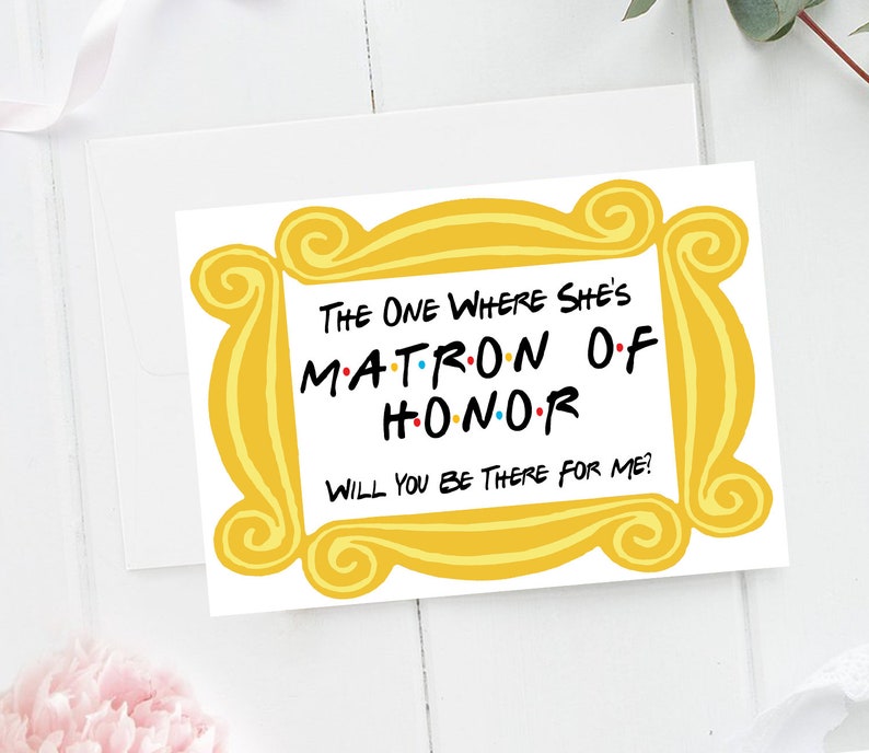 Puede incluir: Una tarjeta amarilla con un marco dorado alrededor de los bordes. El texto dentro del marco dice "The One Where She's Matron of Honor. Will You Be There For Me?"