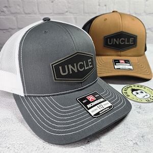 May include: Two trucker hats with the word "UNCLE" on a black patch. One hat is gray with a white mesh back, the other is tan with a black mesh back. Both have a Richardson 112 tag.