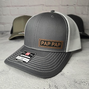 May include: Gray and white trucker hat with a brown leather patch that says "PAP PAP".