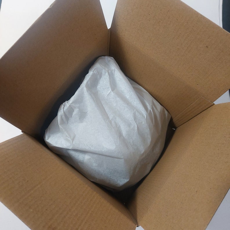 May include: A brown cardboard box with a white tissue paper lining. The box is open and the tissue paper is crumpled.