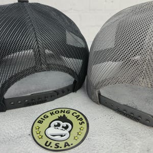 May include: Two trucker hats with mesh backs. One is dark gray, the other is light gray. Both have adjustable snap closures and the Richardson brand name. A sticker with a monkey graphic and the text "BIG KONG CAPS U.S.A." is also visible.
