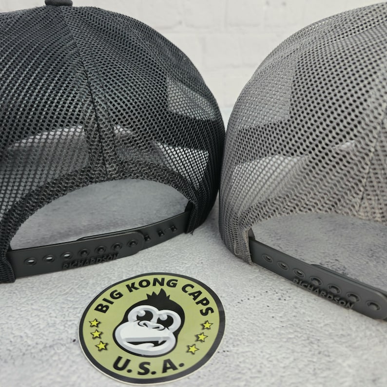 May include: Two trucker hats with mesh backs. One is dark gray, the other is light gray. Both have adjustable snap closures and the Richardson brand name. A sticker with a monkey graphic and the text "BIG KONG CAPS U.S.A." is also visible.
