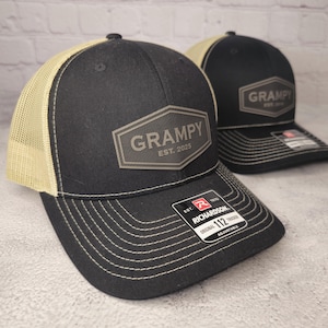 May include: Two black and tan trucker hats with a brown leather patch that says "GRAMPY EST. 2025".