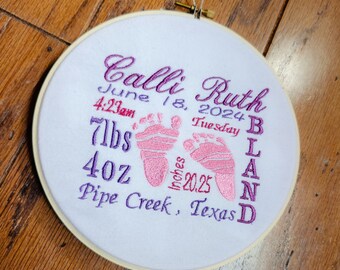 May include: A white embroidery hoop with pink and purple embroidery. The embroidery includes the name "Calli Ruth", the date "June 18, 2024", the time "4:23am", the day of the week "Tuesday", the weight "7lbs", the length "20.25 inches", and the location "Pipe Creek, Texas".