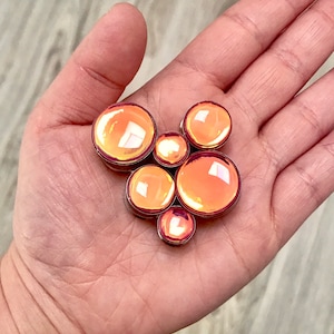 Puede incluir: Un juego de seis expansores de oreja de color naranja iridiscente de diferentes tamaños. Los expansores están hechos de acrílico y tienen un acabado liso y pulido.