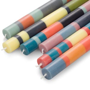 May include: A set of colourful striped candles, each with a different combination of colours, including teal, yellow, orange, grey, and pink.