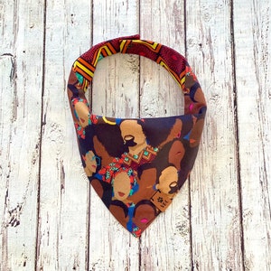 May include: A triangular bandana with a colorful pattern of brown, red, blue, and yellow. The pattern features multiple illustrations of women's faces.