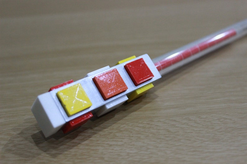 May include: A white plastic device with three colored buttons. The buttons are red, orange, and yellow. The device is attached to a clear plastic tube.