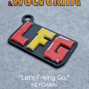Peut inclure: Un porte-clés imprimé en 3D noir avec les lettres "LFG" en rouge, jaune et blanc. Le porte-clés est un article promotionnel pour le film "Deadpool & Wolverine" et comprend le texte "Let's F-king Go."