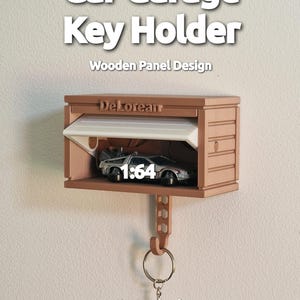 May include: A wooden key holder in the shape of a car garage, with the text "Car Garage Key Holder" at the top. The garage door is open, revealing a miniature DeLorean car. The text "1:64" is visible. A key ring hangs below.