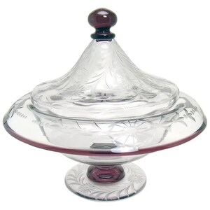 May include: A clear glass candy dish with a lid and a purple base. The dish is decorated with an etched floral design.