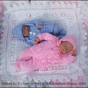 May include: Two knitted baby outfits, one in pink and one in blue, are laid out on a white crocheted blanket. The outfits are complete with matching hats. The blanket has a delicate lace pattern.  Pattern B2 © Claire @ Baby & Doll Handknit Designs 2006