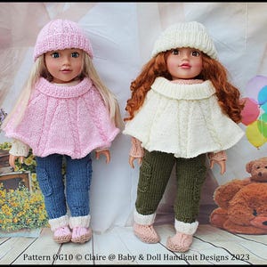 Op de afbeelding: Twee poppen in handgebreide outfits. Eén pop draagt een roze hoed, cape, blauwe jeans en roze laarzen. De andere pop draagt een crèmekleurige hoed en cape, een groene broek en roze laarzen. De outfits zijn handgemaakt.