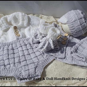 May include: A handmade baby outfit set in white and gray, including a sweater, shorts, booties, and a cap. The set features wooden buttons and a textured knit pattern. The text "Pattern E59 © Claire @ Baby & Doll Handknit Designs 2025" is visible.