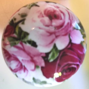 May include: A white ceramic knob with a pink and red rose floral pattern.