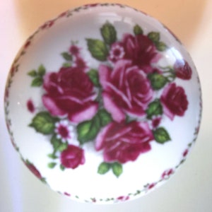 May include: A white ceramic knob with a floral design featuring pink roses and green leaves.